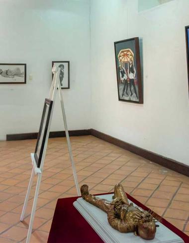 Vista panorámica de la exposición "Orgullo de mis raíces: Copanatoyac" en una sala del Museo Universitario José Juárez. Las pinturas de Miguel Altamirano Velázquez se exhiben en los muros junto con cédulas informativas, mostrando escenas inspiradas en la danza del Tekuanimej y las tradiciones de Copanatoyac, Guerrero.