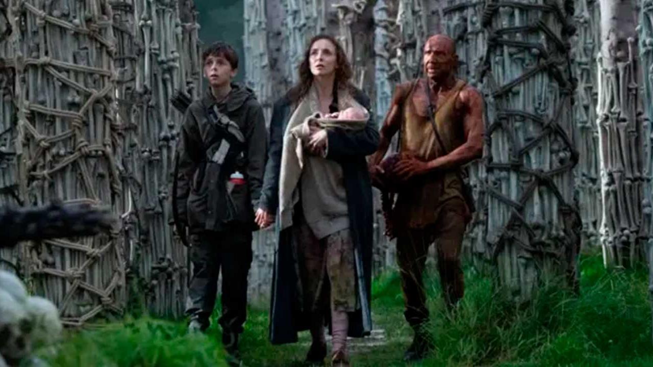 Grupo de supervivientes camina entre estructuras óseas en un entorno postapocalíptico en la película 28 Años Después.