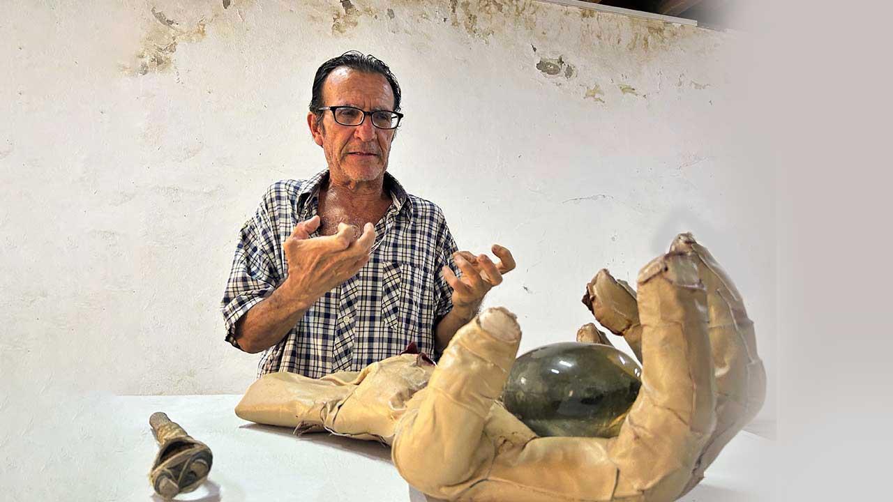 Fotografía de portada del escultor Jorge Alfaro posando junto a su obra en el Fortín Álvarez. El artista posa con su mano real como  está en la escultura con forma de mano humana texturizada con piel de cordero y cicatrices, montada sobre un cubo.