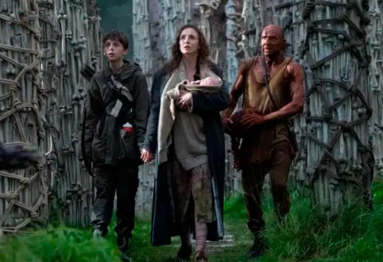 Grupo de supervivientes camina entre estructuras óseas en un entorno postapocalíptico en la película 28 Años Después.