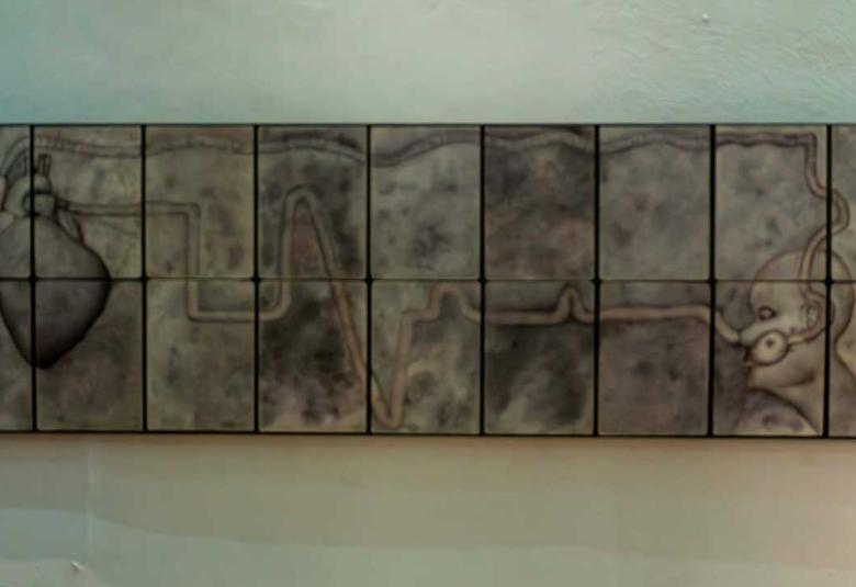 "Obra de arte titulada 'Transfusión de identidad' por Everardo Reyes. Serie de lienzos dispuestos horizontalmente que muestran un corazón humano conectado mediante una línea ondulada a una figura humana estilizada con auriculares. El fondo es gris oscuro con texturas orgánicas. Representa la conexión entre emociones, identidad y tecnología