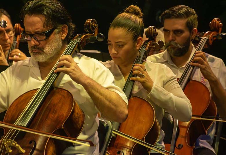 Tres músicos interpretando en el violonchelo durante el Concierto Especial de Verano de la Orquesta Filarmónica de Acapulco