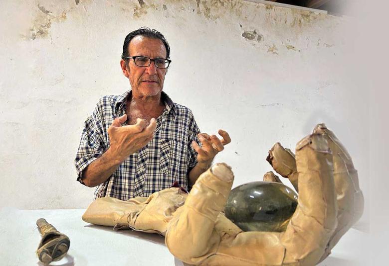 Fotografía de portada del escultor Jorge Alfaro posando junto a su obra en el Fortín Álvarez. El artista posa con su mano real como  está en la escultura con forma de mano humana texturizada con piel de cordero y cicatrices, montada sobre un cubo.