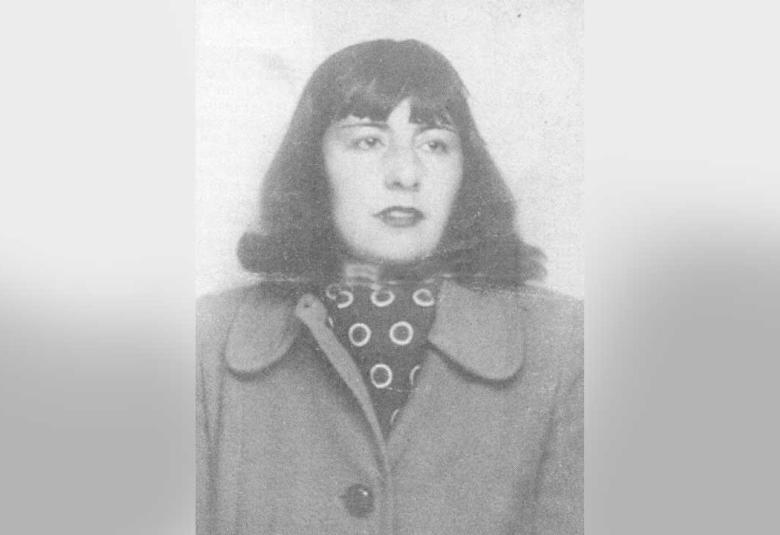 Fotografía en blanco y negro de María Luisa Bombal, tomada de su pasaporte. Ella es una mujer joven con cabello oscuro hasta los hombros, peinado en un bob con flequillo. Mira directamente a la cámara con una expresión seria. Viste un abrigo oscuro con solapas anchas y debajo, un pañuelo de cuello con un patrón de lunares o círculos blancos. La foto tiene un aspecto vintage y está enmarcada por bordes grises y borrosos.