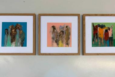 Tres obras pictóricas del artista guerrerense Héctor Massiel montadas en una pared blanca durante la exposición «Le Mexique en Couleurs» en el Teatro del Altigone, Francia. Las pinturas muestran figuras estilizadas y colores vibrantes sobre bastidores que conservan texturas orgánicas.